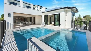 A modern house with a swimming pool, an outdoor dining area, and a covered patio. - Vanderbilt Luxury | Private Salt Pool & Spa | Minutes to Vanderbilt Beach (Naples)