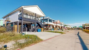 Een rij strandhuisjes met balkons, een heldere lucht en een verharde looppad.