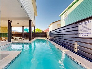 A swimming pool with a wooden fence and a sign listing pool rules. - RFL139 Midnight Cove, Private Heated Pool, Propane Grill, Parking for 3 (Port Aransas)