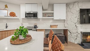 A modern kitchen with white cabinets, a microwave, and a stone wall. - 🏔️Brand New Listing~Studio Premier 204🏔️ (Snowmass Village)