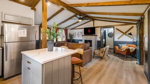 A spacious kitchen with a central island, wooden beams, a built-in fridge, and a TV above the fireplace. - Riverfront- 3 Hole Golf Course - Pool - Hot Tub - Sauna - 2 Game Rooms (Elkton)