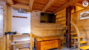 A wooden interior with a TV mounted on the wall, a wooden bench, and a spiral staircase. - LA MAISON DU PAPE - BONNEVAL SUR ARC (BONNEVAL SUR ARC)