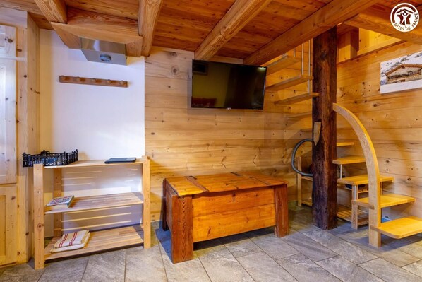 A wooden interior with a TV mounted on the wall, a wooden bench, and a spiral staircase. - LA MAISON DU PAPE - BONNEVAL SUR ARC (BONNEVAL SUR ARC)