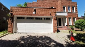 A two-story brick house with a white garage door, a mailbox, and a street lamp.