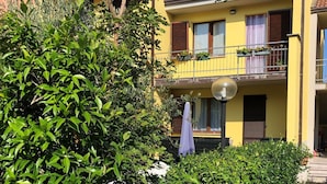 A yellow building with a balcony, surrounded by greenery. - Nice apartment for 4 people with WIFI, pool, TV and terrace (Pignone)