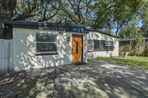A single-story building with a front door, two windows, and a small porch area.