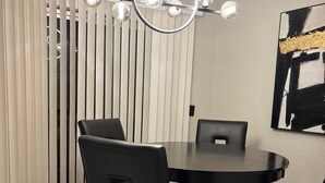 A modern dining area with a round table, black chairs, and a ceiling light fixture.