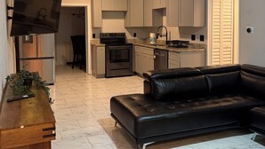 A modern kitchen with grey cabinets, a black stove, and a ceiling fan.