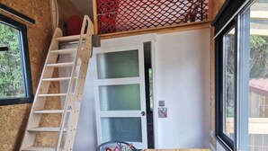 A compact room with a wooden table, a ladder, a chair, and a window. - LA CHARMOTTE - Verbiesles (Verbiesles)