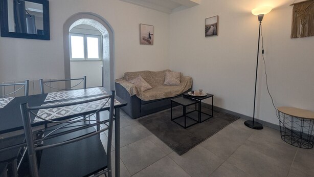 A modern living room with a dining area, featuring a sofa, coffee table, and a dining table with chairs. - Au petit Café - Châteauvillain (Châteauvillain)