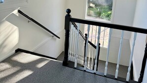 A staircase with a black and white railing, carpeted steps, and a hanging light fixture.