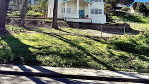 A two-story house with a green door and white exterior, surrounded by trees and a grassy yard.