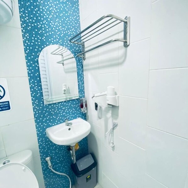 Un baño con lavamanos, espejo y pared de mosaicos azules.