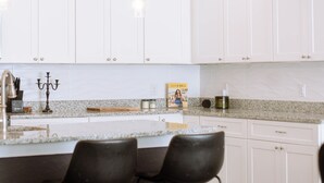 A modern kitchen with white cabinets, a granite countertop, and two black bar stools. - Just minutes from River walk and downtown San Antonio, (San Antonio)