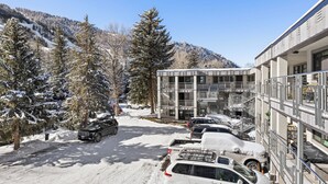 Un’area di parcheggio innevata con auto e un edificio a più piani e balconi.