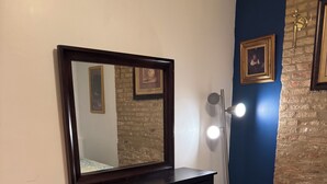 A bedroom with a dark wooden dresser, a large mirror, a patterned rug, and a blue accent wall. - Peaceful 1-bedroom apartment with AC in vibrant Chicago (Chicago)