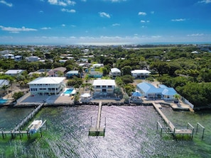 A coastal residential area with houses, a dock, and a clear view of the ocean.