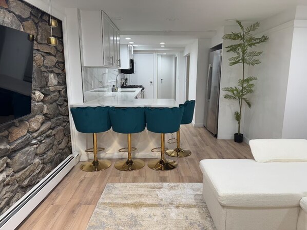 Una cocina moderna con armarios blancos, una isla central y taburetes de bar color turquesa.