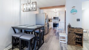 Een moderne keuken met een eethoek, met een centraal kookeiland, ingebouwde apparatuur en een decoratieve klok aan de muur.
