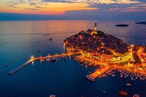 A coastal town with a prominent tower, a marina with boats, and a waterfront promenade.