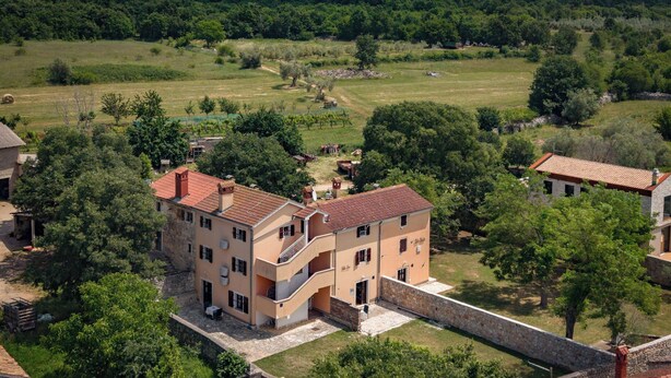 A multi-story building with balconies, surrounded by greenery and a stone wall. - Istrian Countryside House Iva, Rovinj-Krmed, Croatia (Krmed)
