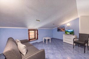 Ein Wohnzimmer mit einer Couch, einem Fernseher und einem Sessel.
