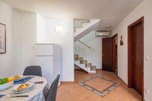 Ein Essbereich mit einem Tisch für zwei Personen, einem Kühlschrank und einer Treppe, die zu einer oberen Etage führt.