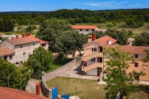 A residential area with houses featuring red-tiled roofs and stone walls, surrounded by greenery and trees. - Istrian Countryside House Iva, Rovinj-Krmed, Croatia (Krmed)