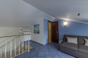 A living room with a sofa, a staircase, and a door.