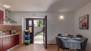 A compact kitchen with a dining area, a red cabinet, a stove, and a tiled floor. - Istrian Countryside House Iva, Rovinj-Krmed, Croatia (Krmed)