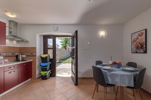 A compact kitchen with a dining area, a red cabinet, a stove, and a tiled floor. - Villa Iva, Krmed, Croatia (Krmed)