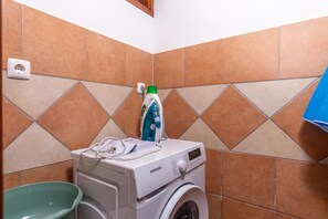 Eine Waschmaschine mit Frontlader, einer grünen Trommel und einem Stromanschluss.