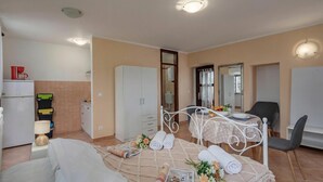 Une chambre comprenant un lit, un bureau, une chaise, une armoire et un petit coin cuisine.