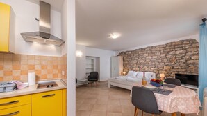 Une cuisine moderne avec des armoires jaunes, une cuisinière encastrée et un mur en pierre.