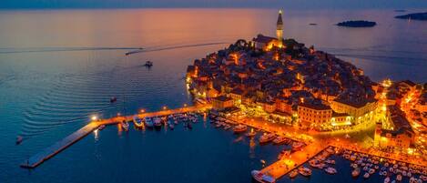 A coastal town with a prominent tower, a marina with boats, and a waterfront promenade.