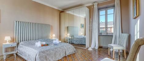 Ett hotellrum med en stor säng, en stol, en spegel och utsikt över omgivningarna.