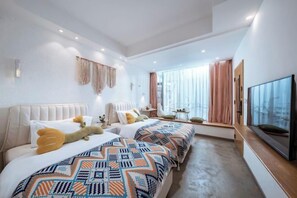 Una habitación de hotel moderna con dos camas, un ventanal con cortinas, un televisor de pantalla plana y una mesita.