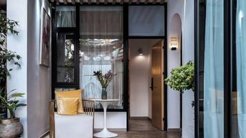 A hotel entrance with a seating area, a small table, and a potted plant.