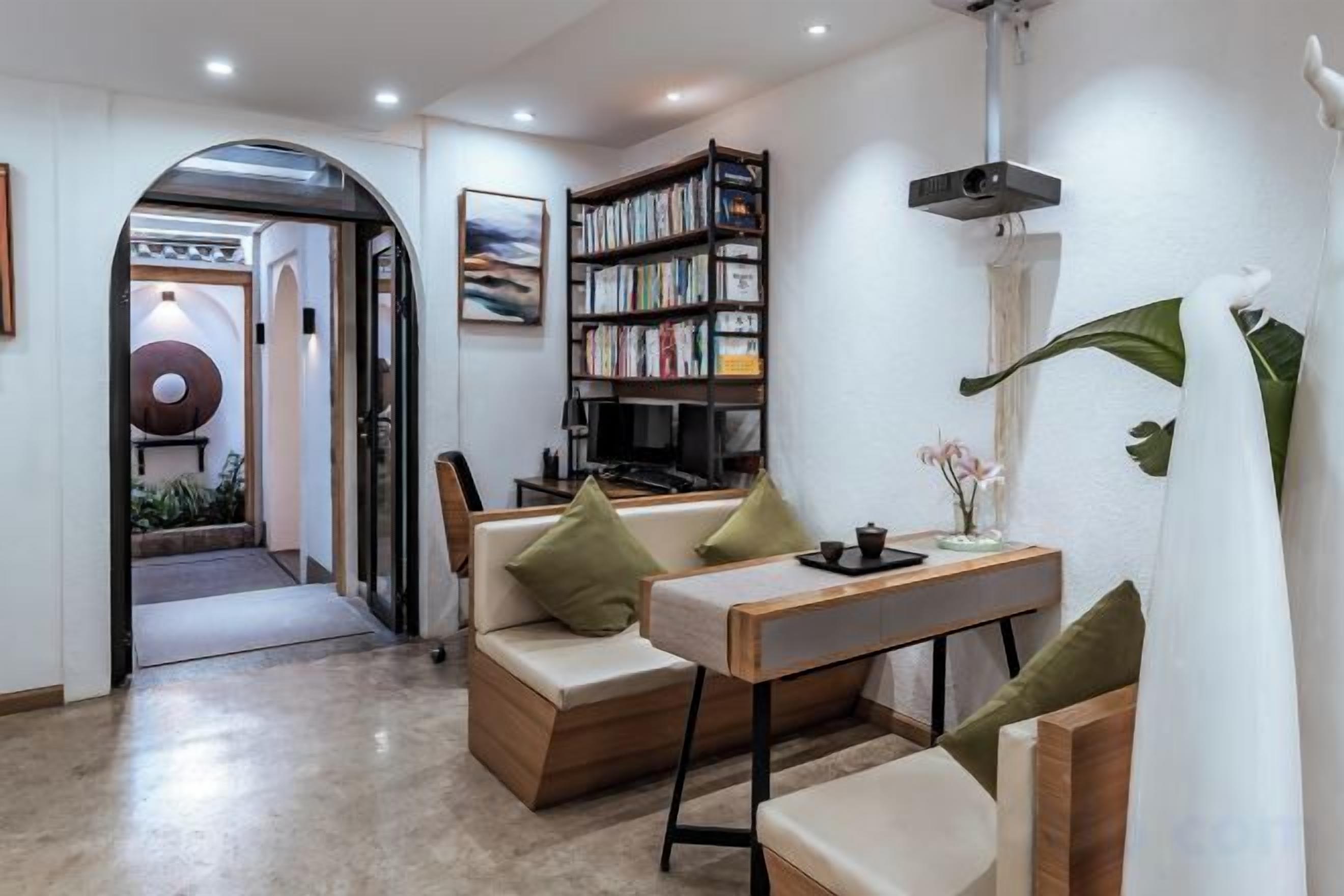 A modern living room with a sofa, a coffee table, a bookshelf, and a dining table.