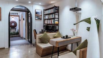 A modern living room with a sofa, a coffee table, a bookshelf, and a dining table.