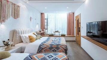 A modern hotel room with a bed, bedside table, TV, and a window with curtains.