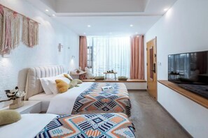 Una habitación de hotel moderna con cama, mesita de noche, televisor y ventana con cortinas.