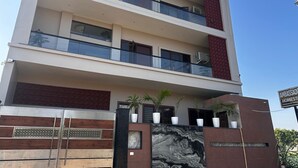 A multi-story residential building with balconies, a decorative gate, and potted plants. - Beautiful Homestay (Agra)