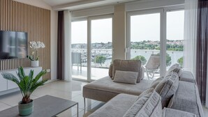 A modern living room with a sofa, a TV, and a view of a marina. - Panoramic Sea view Apartment 3 with Pool, Pula, Croatia (Pula)