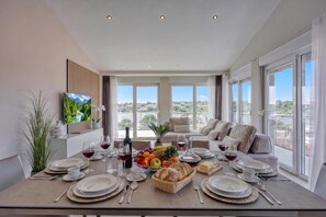 A dining area with a table set for six, a television on the wall, and a view of the outdoors. - Panoramic Sea view Apartment 3 with Pool, Pula, Croatia (Pula)