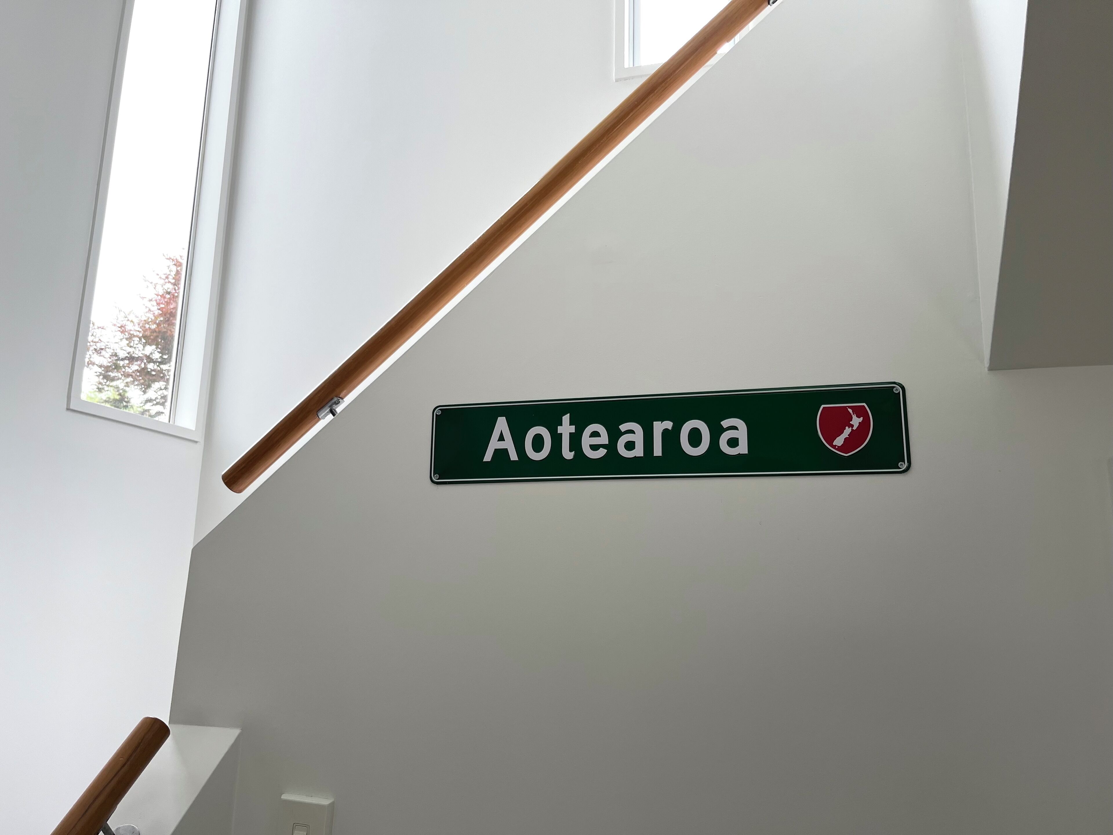 A sign reading "Aotea" with a red shield emblem on a white wall.