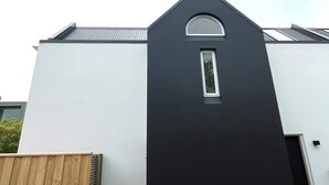 Un bâtiment moderne avec une façade blanche et une entrée de couleur sombre.