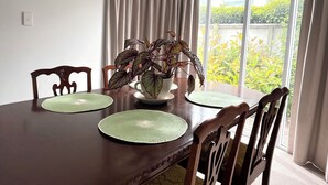 Une table à manger avec quatre chaises, une plante en pot et une fenêtre avec des rideaux.