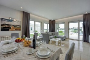 A dining area with a table set for four, a sofa, and a view of the outdoors. - Panoramic Sea view Apartment 1 with Pool, Pula, Croatia (Pula)