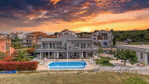 Een moderne villa met zwembad, omgeven door weelderige begroeiing en een prachtig uitzicht op de zonsondergang.